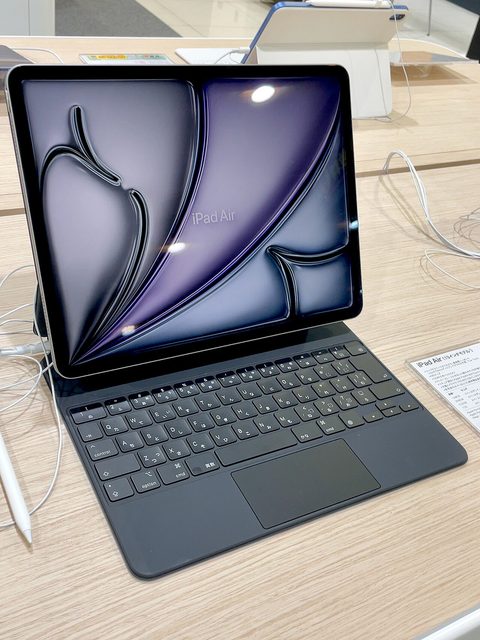 an ipad air 13 inch on a magic keyboard in a store, purple wallpaper on screen