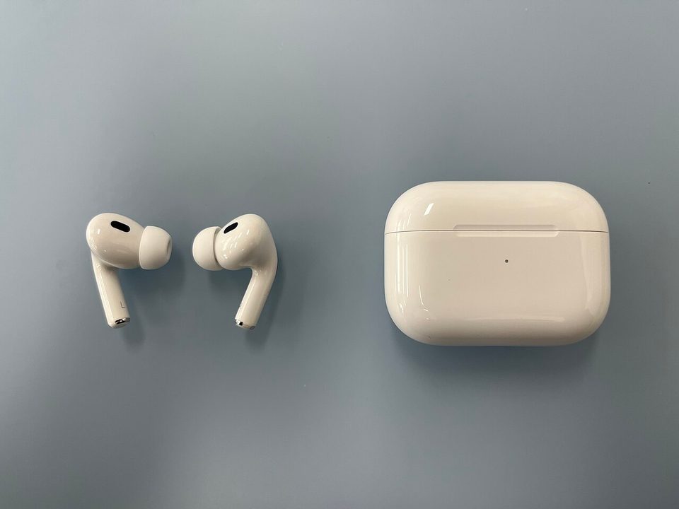 airpods pro second generation earbuds and their white charging case on a gray blue table