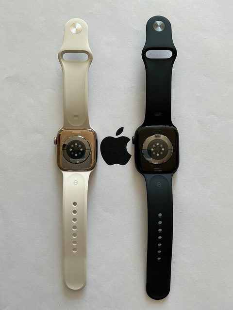 two apple watch series 10 watches, gold and jet black, seen from the back with their sensor arrays
