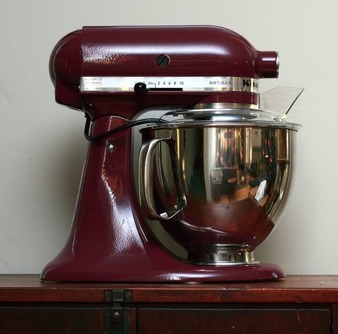 a red kitchenaid artisan stand mixer on a wooden counter