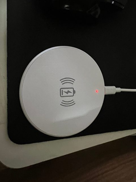 a white wireless charging stand on a bedside table