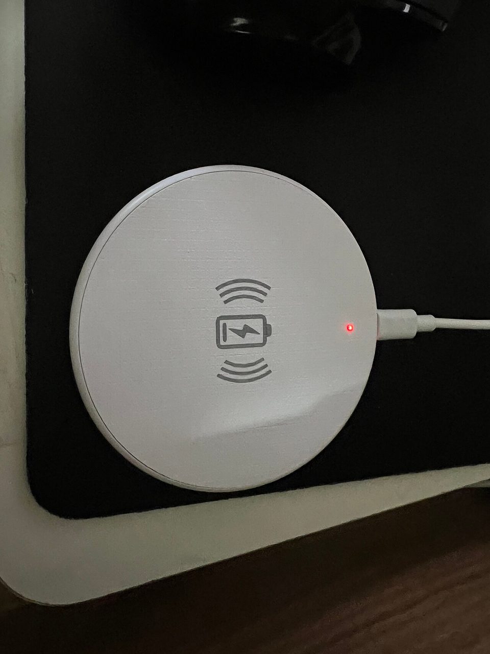a white wireless charging stand on a bedside table