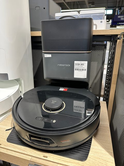 A Roborock robot vacuum with a LiDAR dome on a wooden floor