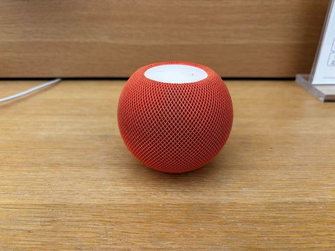 A bright orange HomePod mini smart speaker photographed up close