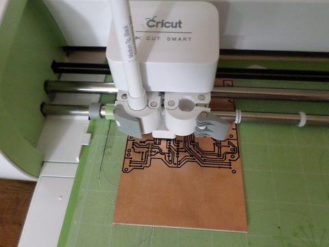 A Cricut cutting machine cutting a design in a bright workspace