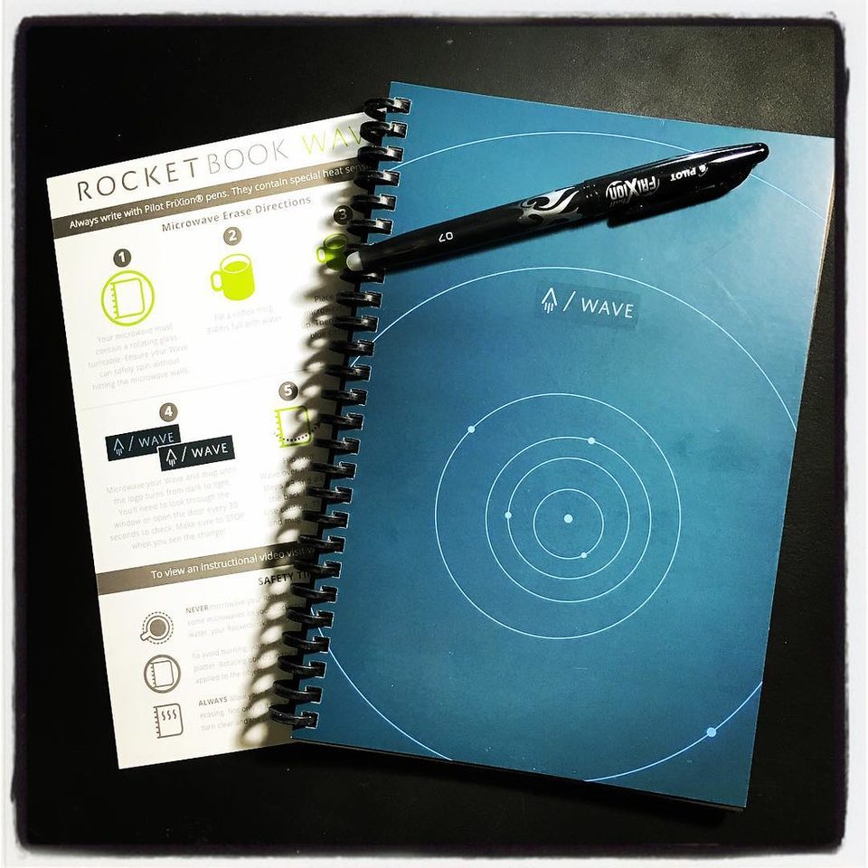 A Rocketbook reusable notebook with a pen and the scanning app on a desk