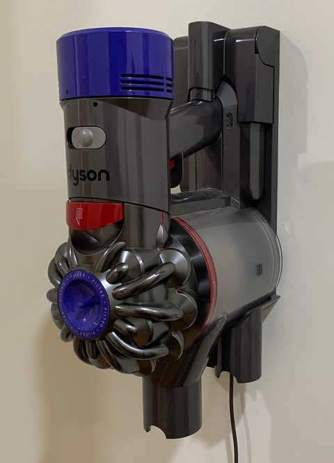 A Dyson cordless vacuum mounted on its wall dock