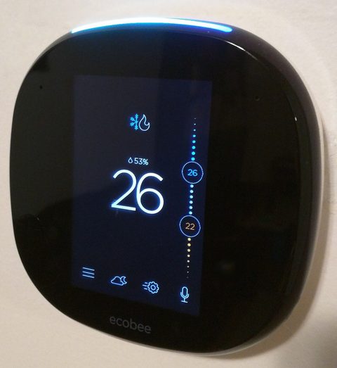 An ecobee4 smart thermostat mounted on a wall, seen from an angle with the home screen showing