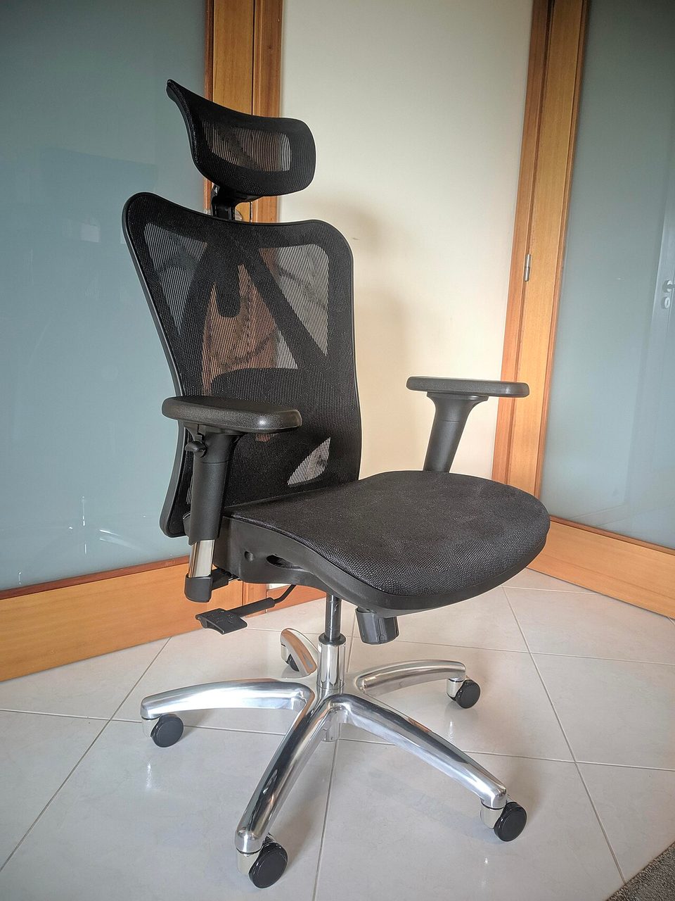 A black mesh office chair with a mesh backrest and adjustable armrests on casters, photographed against a plain wall. This is not the Sand and White Branch chair from this post, it is the closest freely licensed office chair photo I could find.