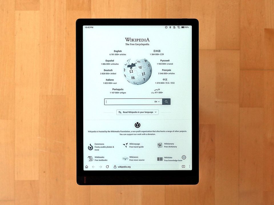 a large boox tab x e-ink tablet showing the wikipedia home page on a wood surface, a bigger sibling of the pocket-sized palma 2, not the palma itself