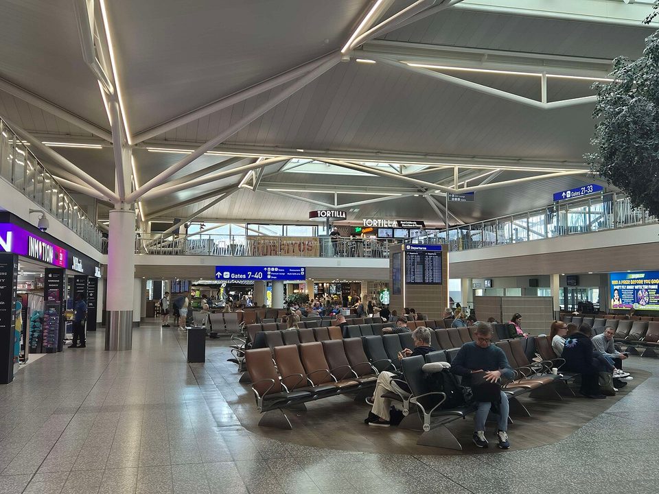 An airport terminal waiting area with seated travelers