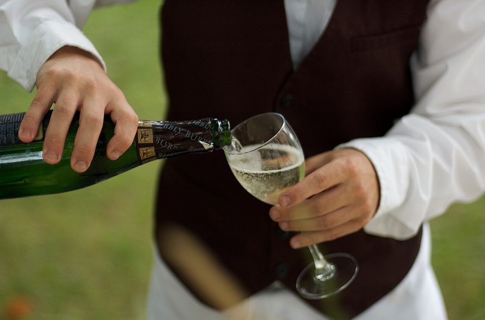 A waiter pouring sparkling wine at a restaurant table