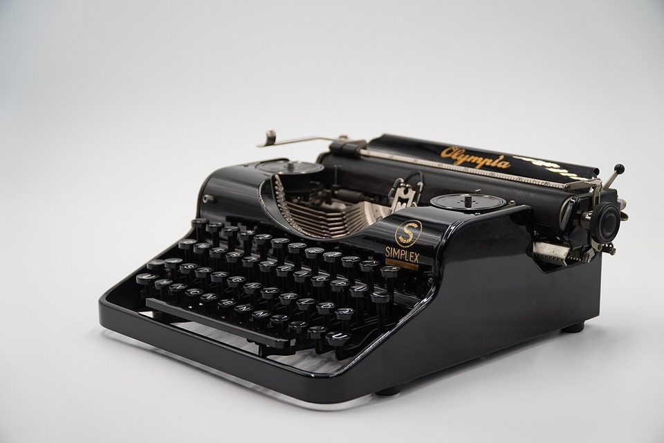 A black Olympia Simplex manual typewriter on a plain white background