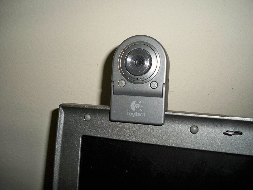 A clip-on webcam perched on top of a laptop screen