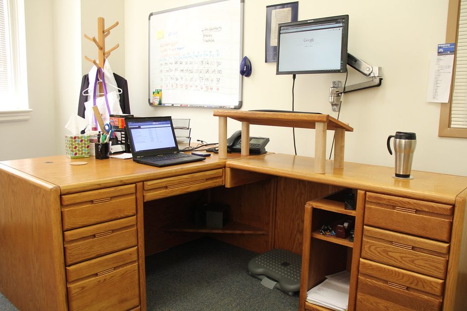 A sit-stand desk raised to standing height, the position the wellness budget promised and almost nobody kept