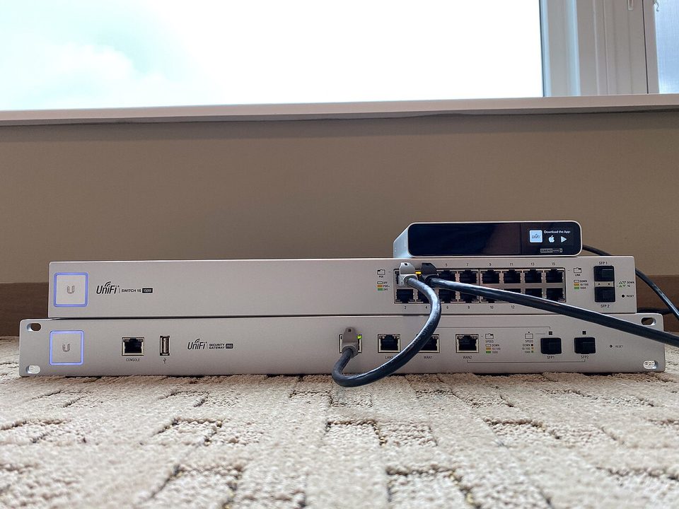 A UniFi Security Gateway Pro and a UniFi 16-port switch, two rack devices stacked on a carpet
