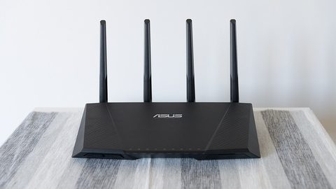 A black ASUS dual-band wireless router with four antennas, photographed from the front