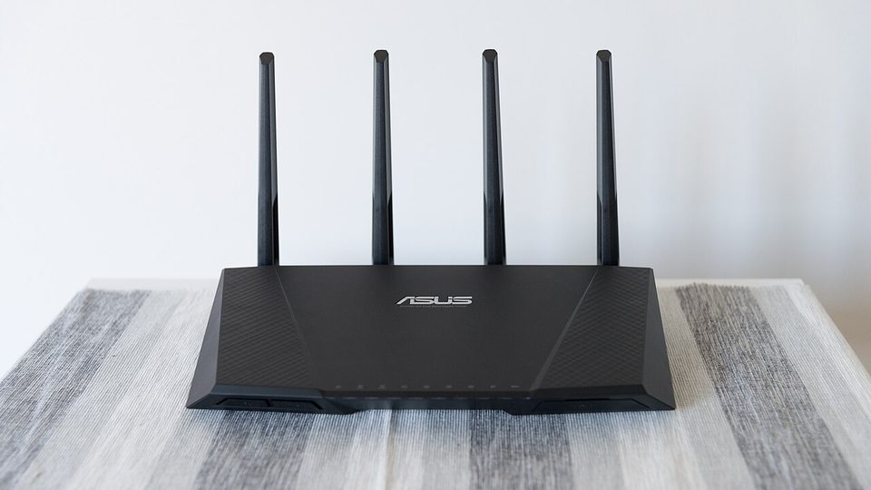 A black ASUS dual-band wireless router with four antennas, photographed from the front