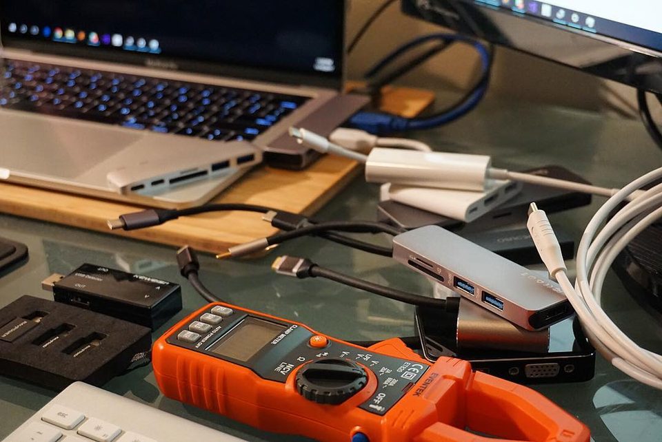 Several USB-C hubs and adapters laid out next to a laptop, the general shape of the 555's category