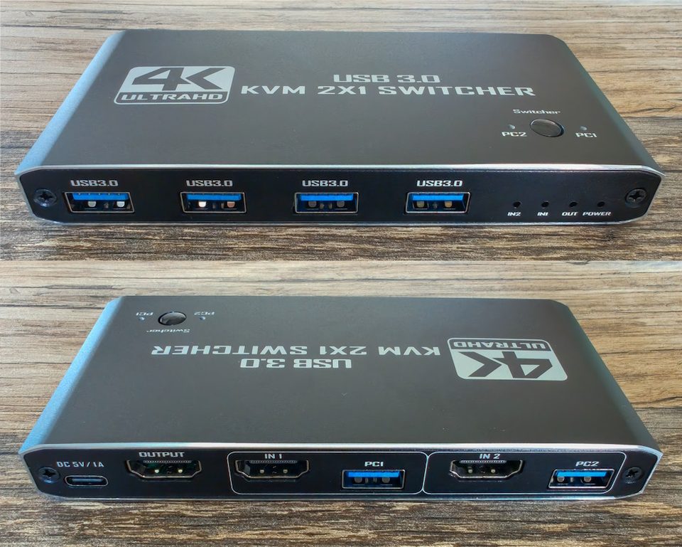A modern KVM switch on a desk with cables running to two computers