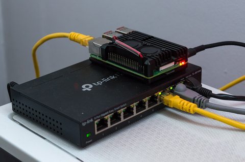 A Raspberry Pi and cabling sitting on top of a desktop network switch