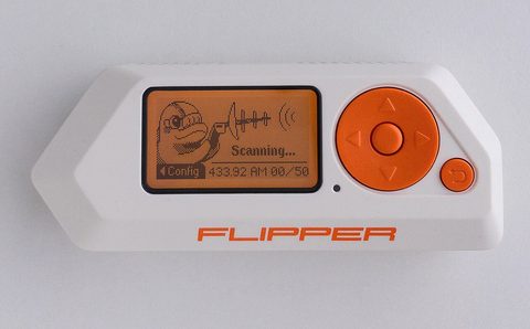 A Flipper Zero handheld device with its dolphin on the monochrome screen, connected by a USB cable