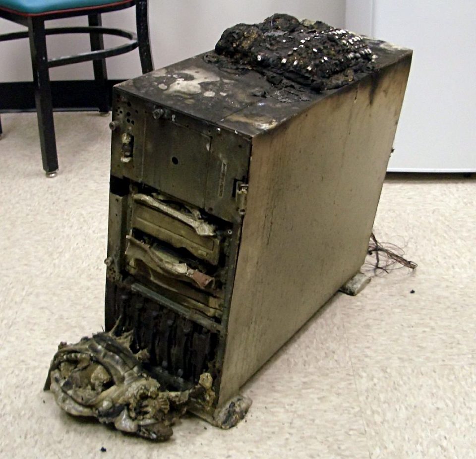 A fire-damaged server pulled from an Oklahoma office fire, its case blackened, with a telephone sitting on top of it