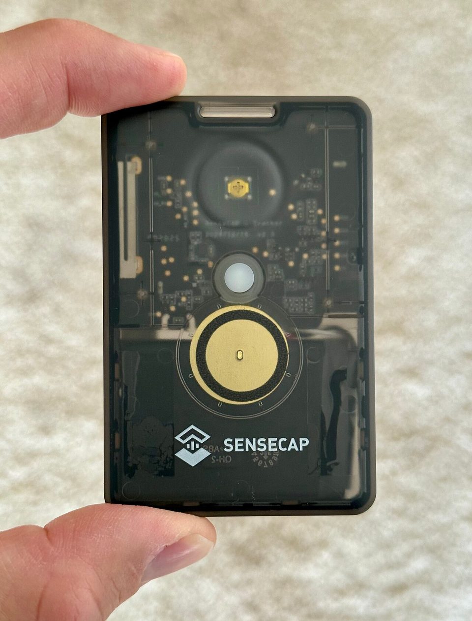 A credit-card-sized Seeed SenseCAP T1000-E Meshtastic tracker photographed flat, showing its rounded corners and small status lights