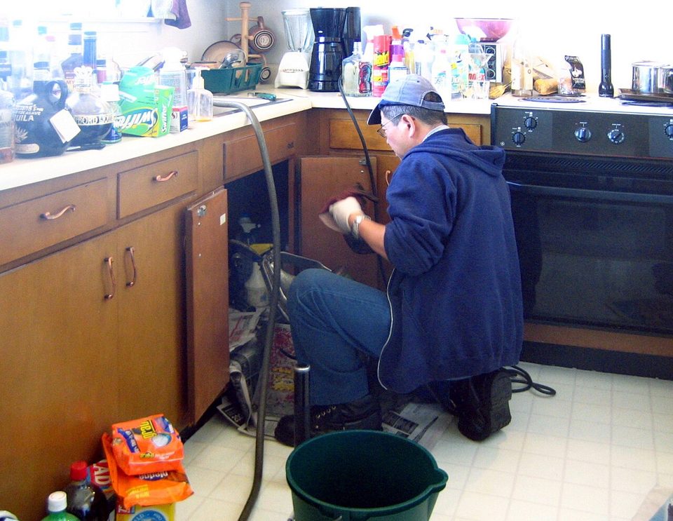 Plumber working on pipework under a sink