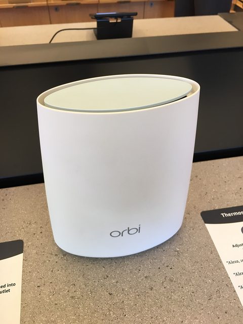 Two white Netgear Orbi mesh wifi units standing on a wooden table