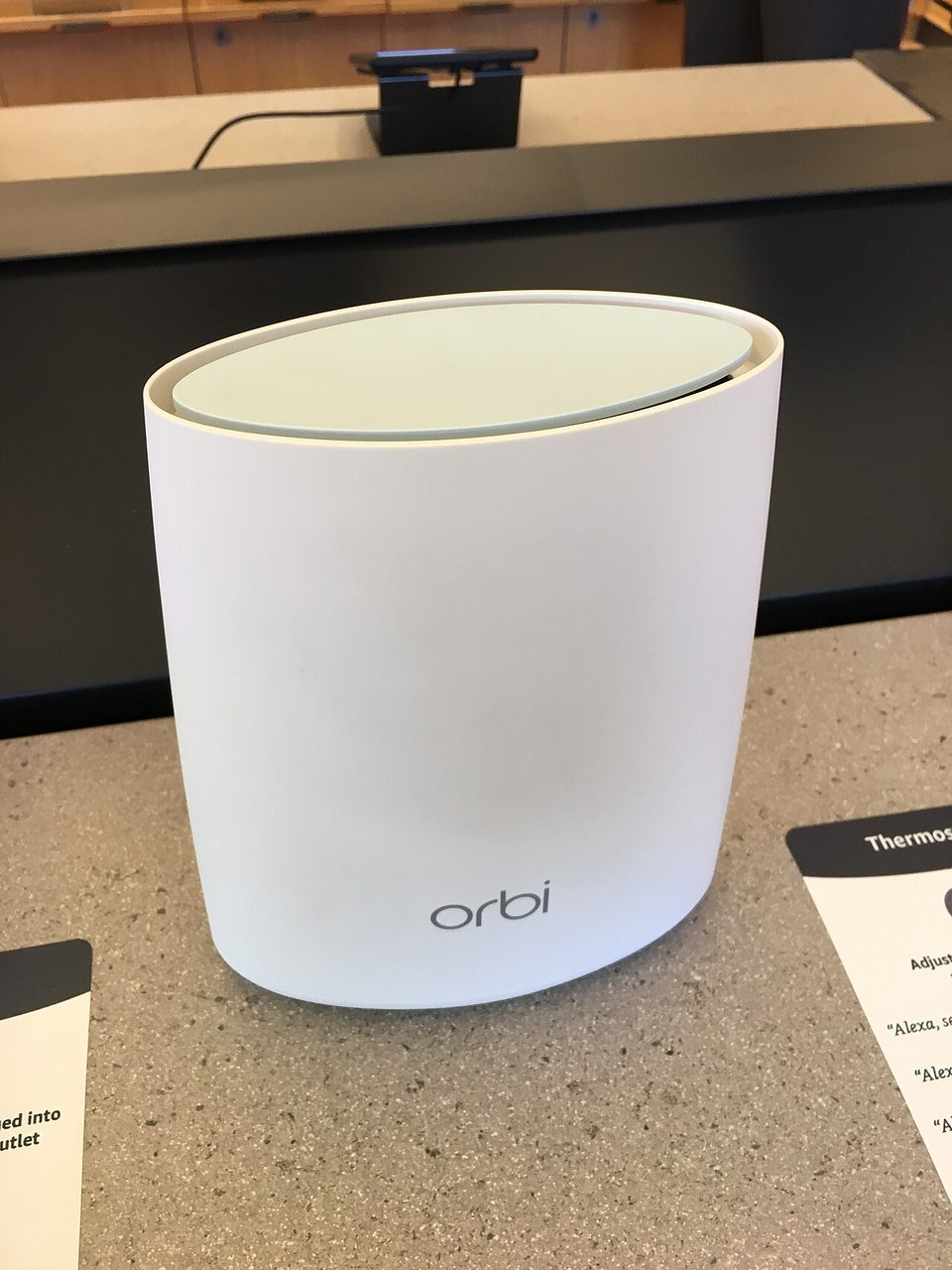 Two white Netgear Orbi mesh wifi units standing on a wooden table