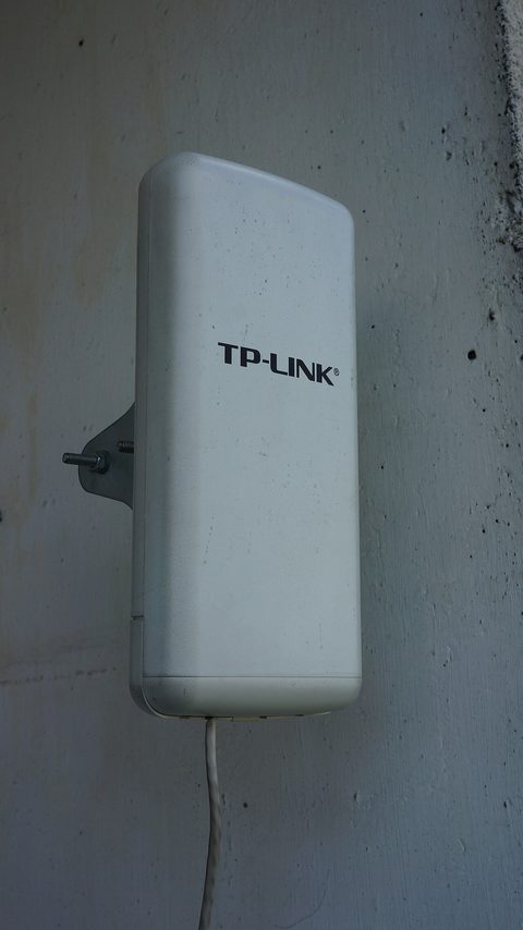 A TP-Link Omada management dashboard on a tablet next to Omada network hardware