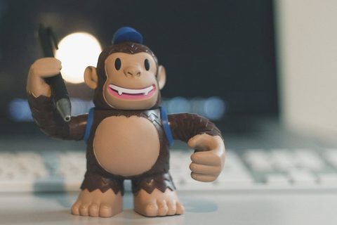 A vinyl toy of Freddie, the Mailchimp chimp mascot, standing in front of a computer keyboard