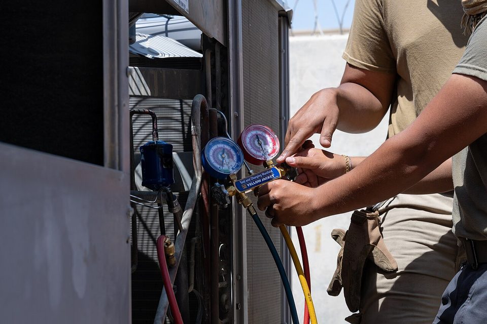 HVAC technicians working on an air conditioning unit outside a building