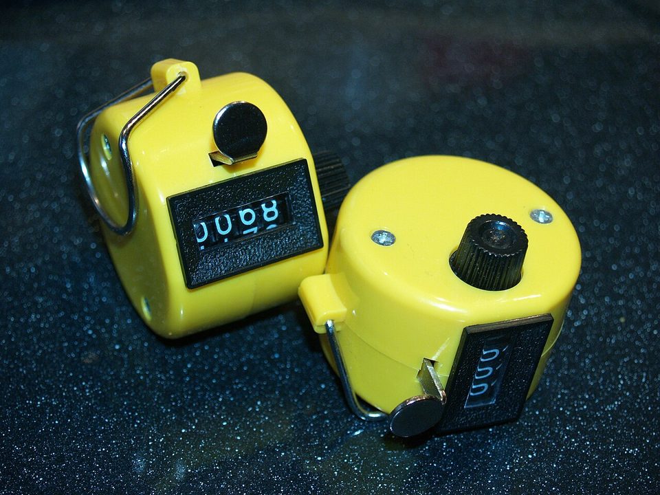 Three mechanical tally counters, the click-to-count kind a person holds in one hand
