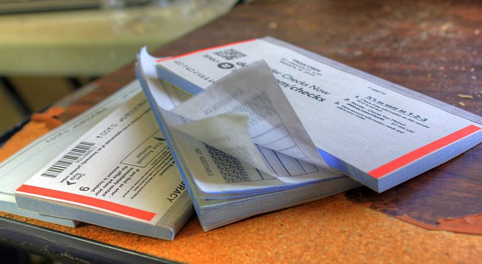 A row of checkbooks and check registers on a table