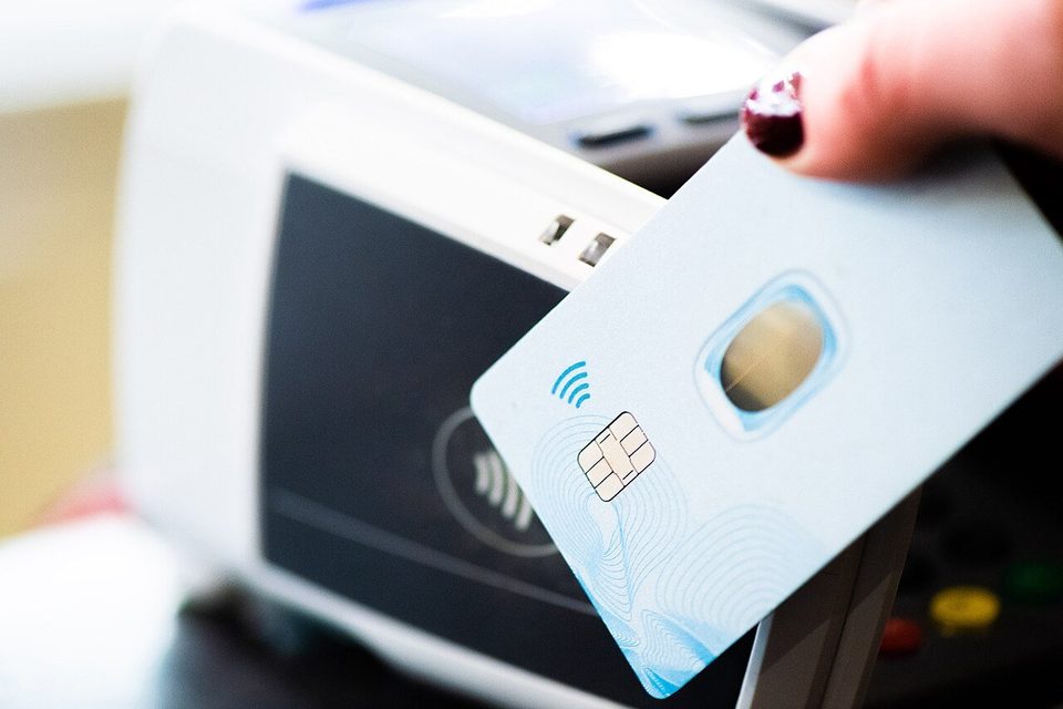 A contactless bank card held up to a card payment terminal